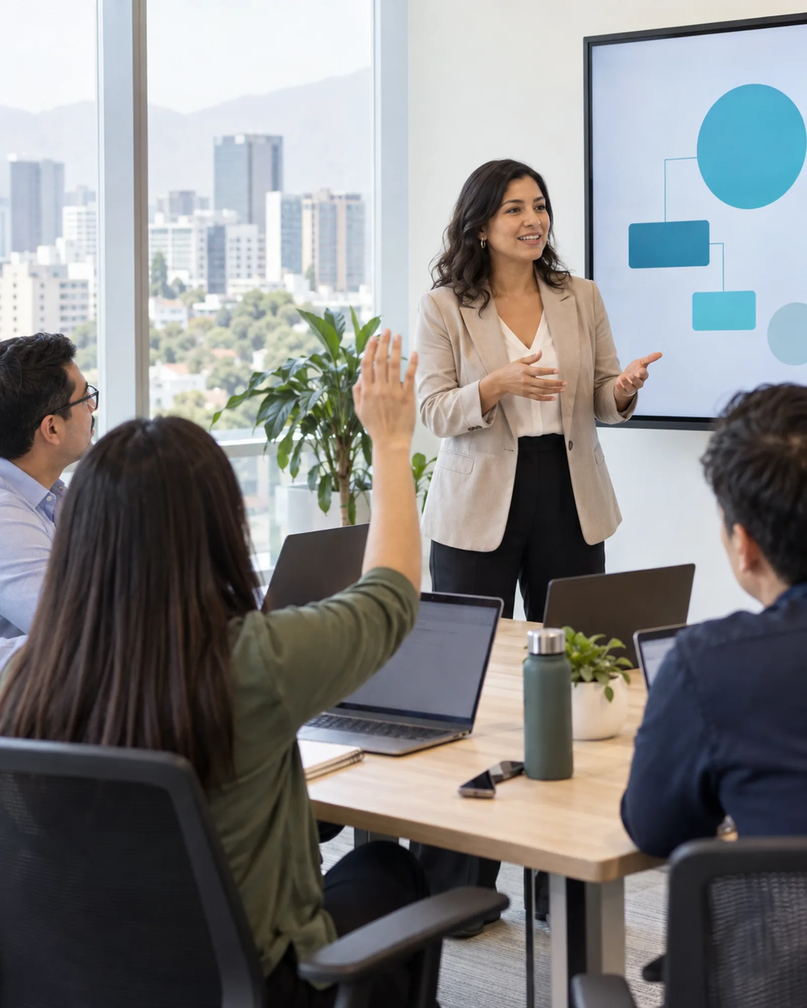 Facilitadora conduciendo un taller de IA; una participante levanta la mano para preguntar
